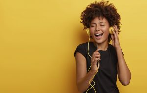 Chica con rizos y cascos amarillos cantando