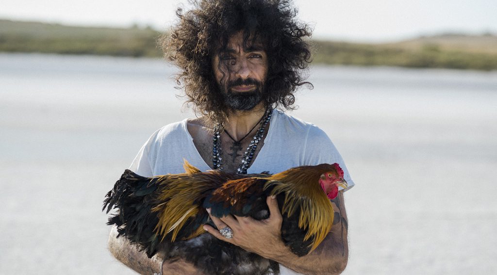 Ara Malikian sujetando una gallina en el desierto